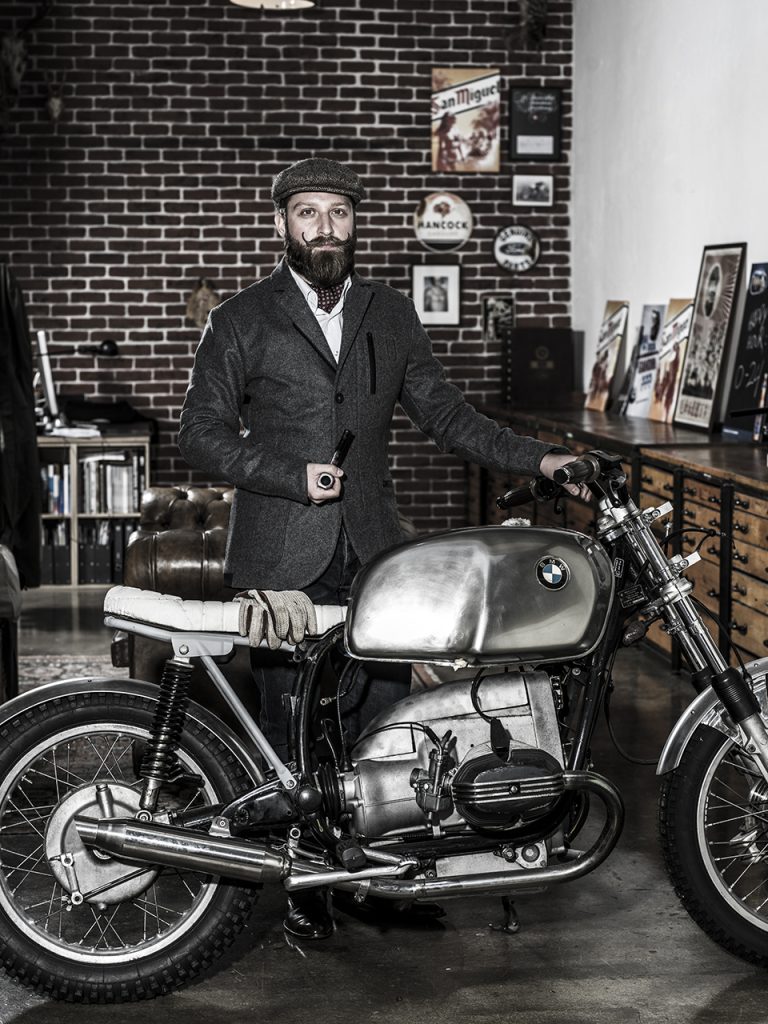 Portrait Felix Cremerius, lehnt an Motorrad in Outdoorjacke